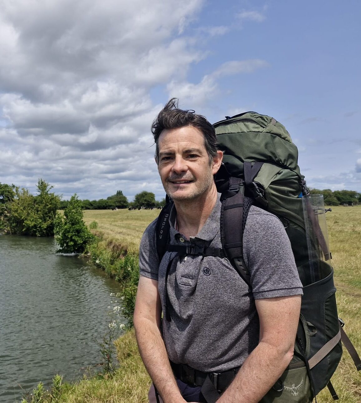 A man, Dr Neil Bailey, Director of Water, Land and Catchments, standing alongside a river.