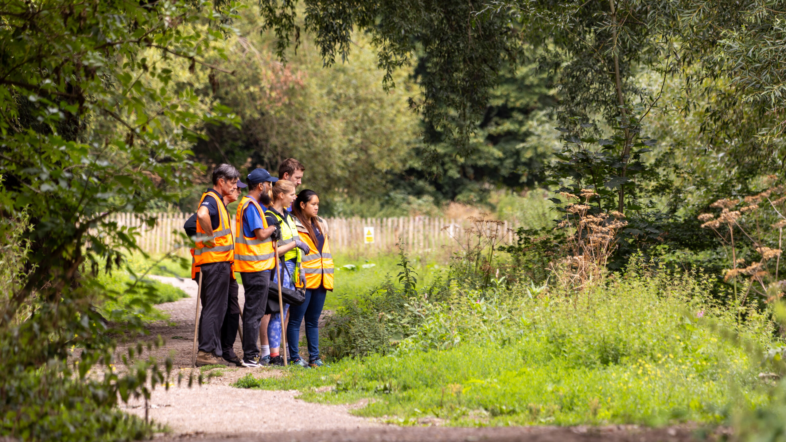 A group of volunteers standing on a path alongside a river.