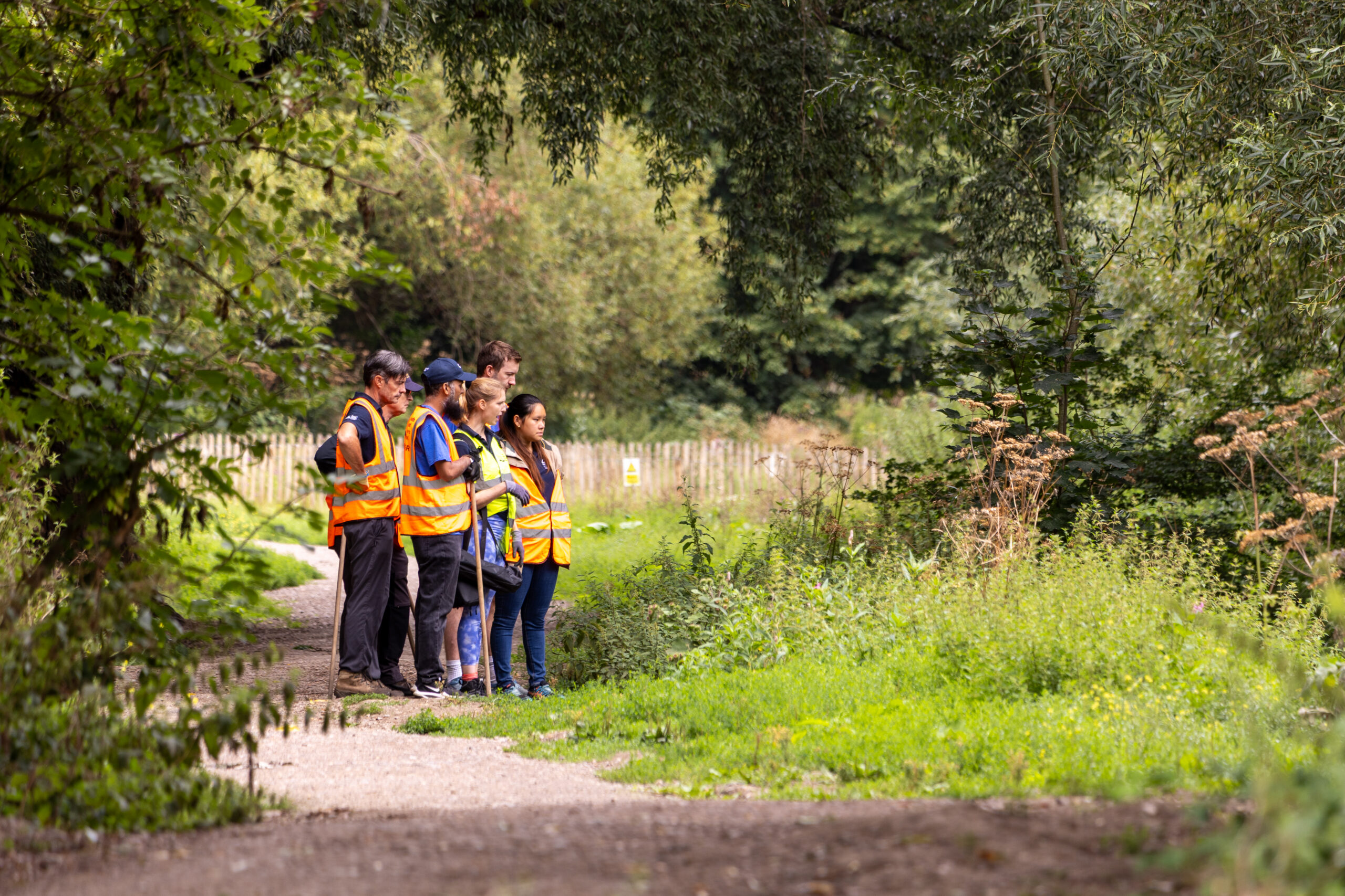 A group of volunteers standing on a path alongside a river.