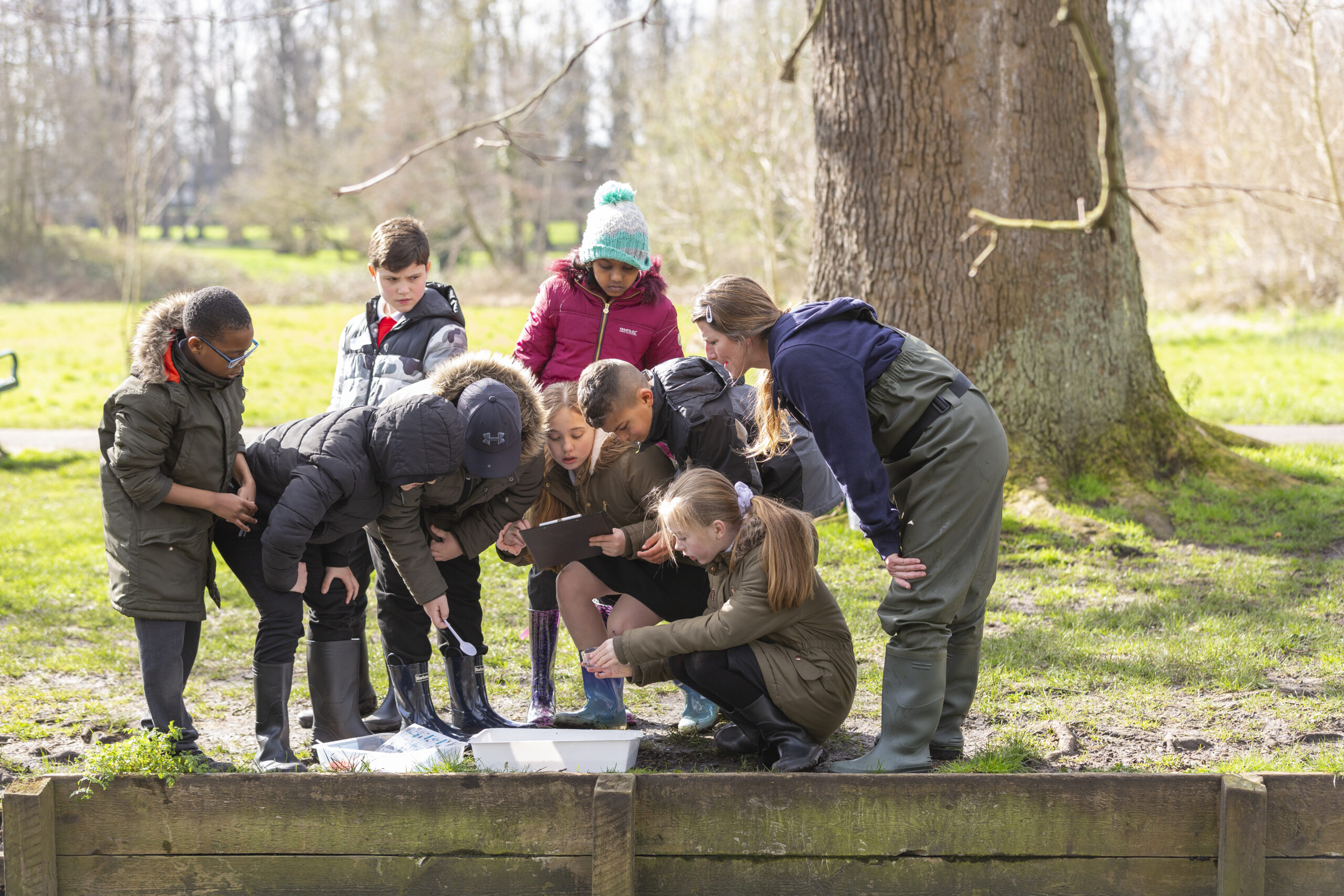 A group of young people standing alongside a river having an education session with a South East Rivers Trust Education Officer.