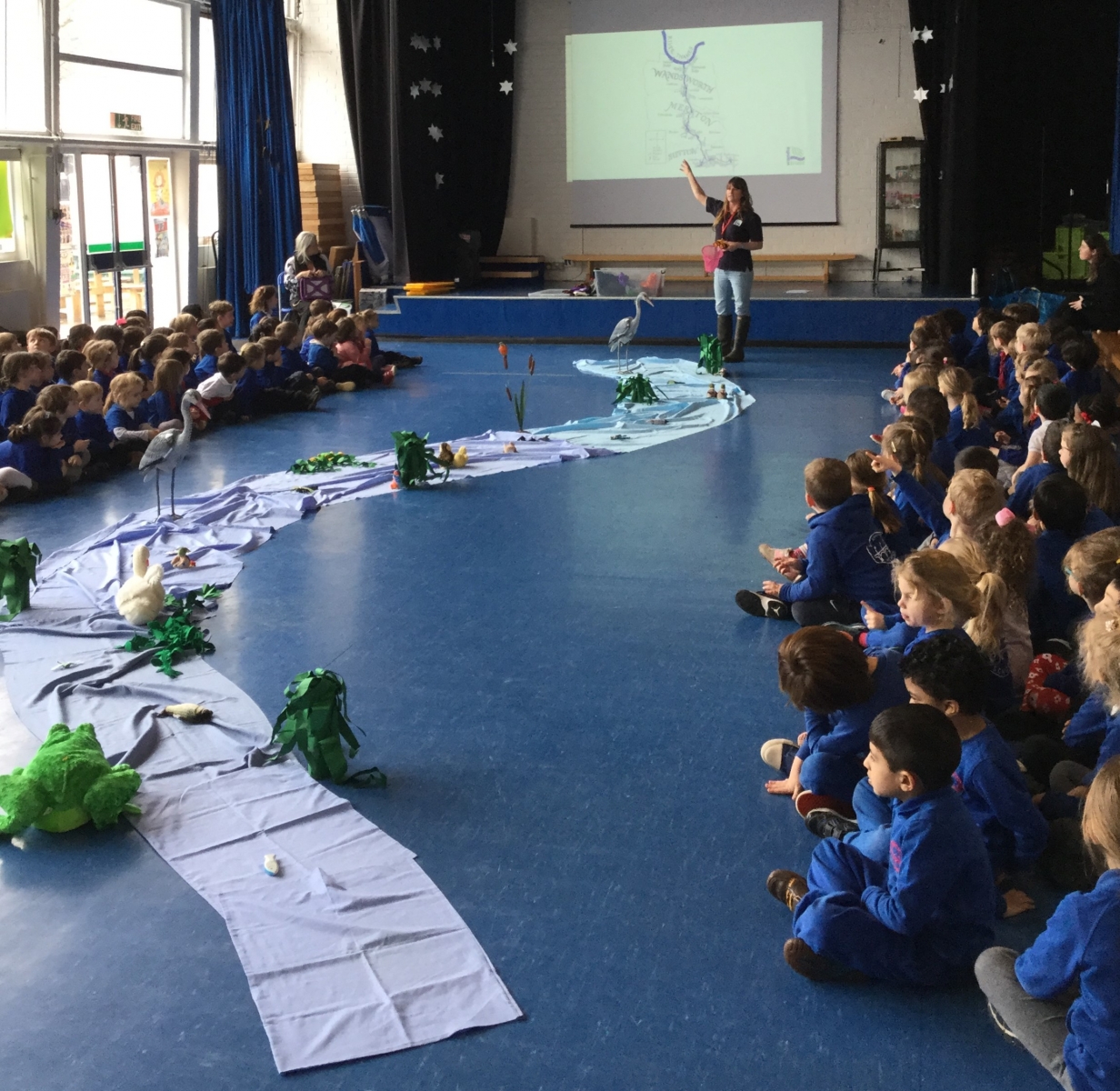 A primary school assembly with an immitation river along the floor showing different animals along the river