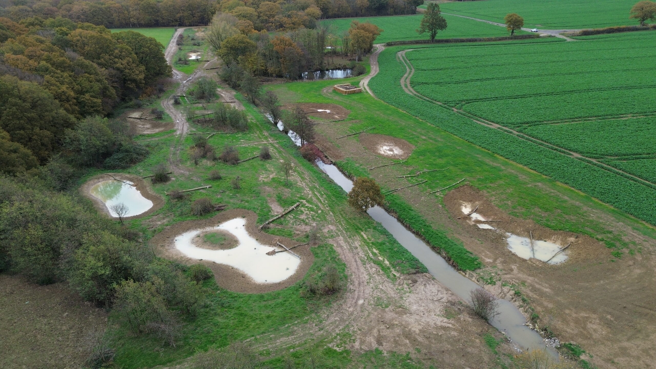 An aerial view of the river flowing through fields with ponds either side for storing water