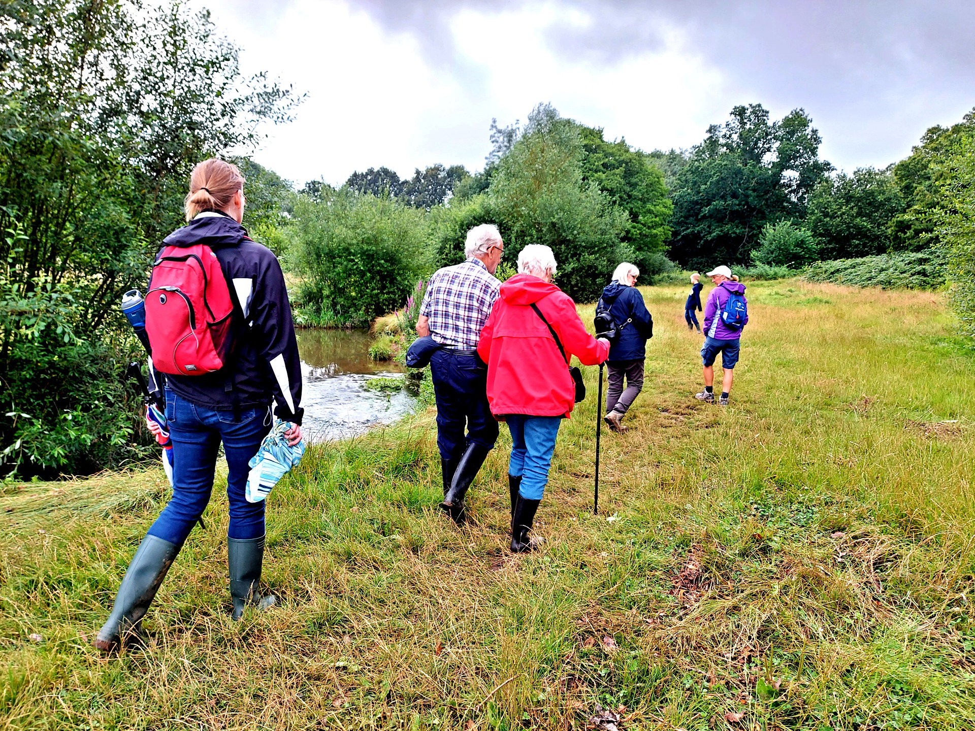 A group of people walking along a river bank.