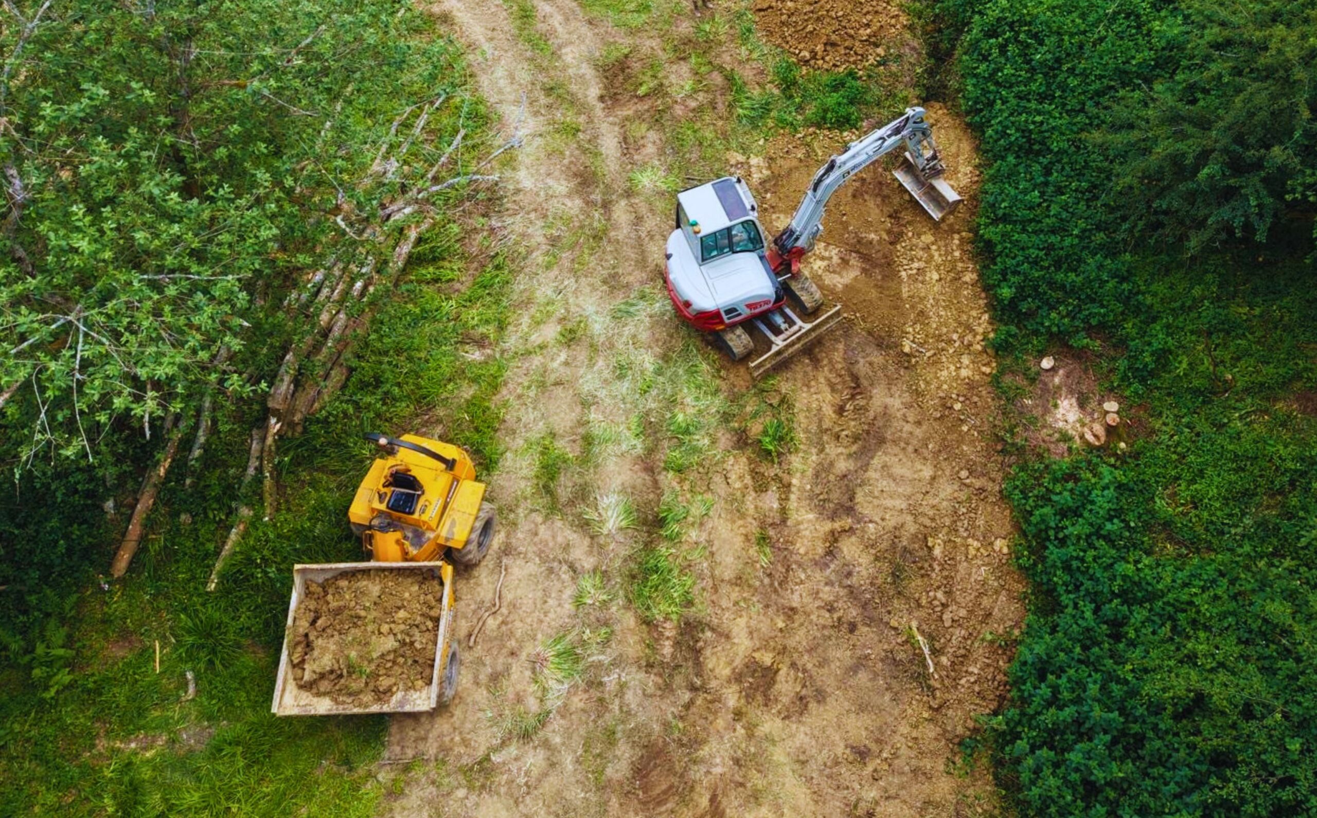 An aerial shot of a two diggers in a field.
