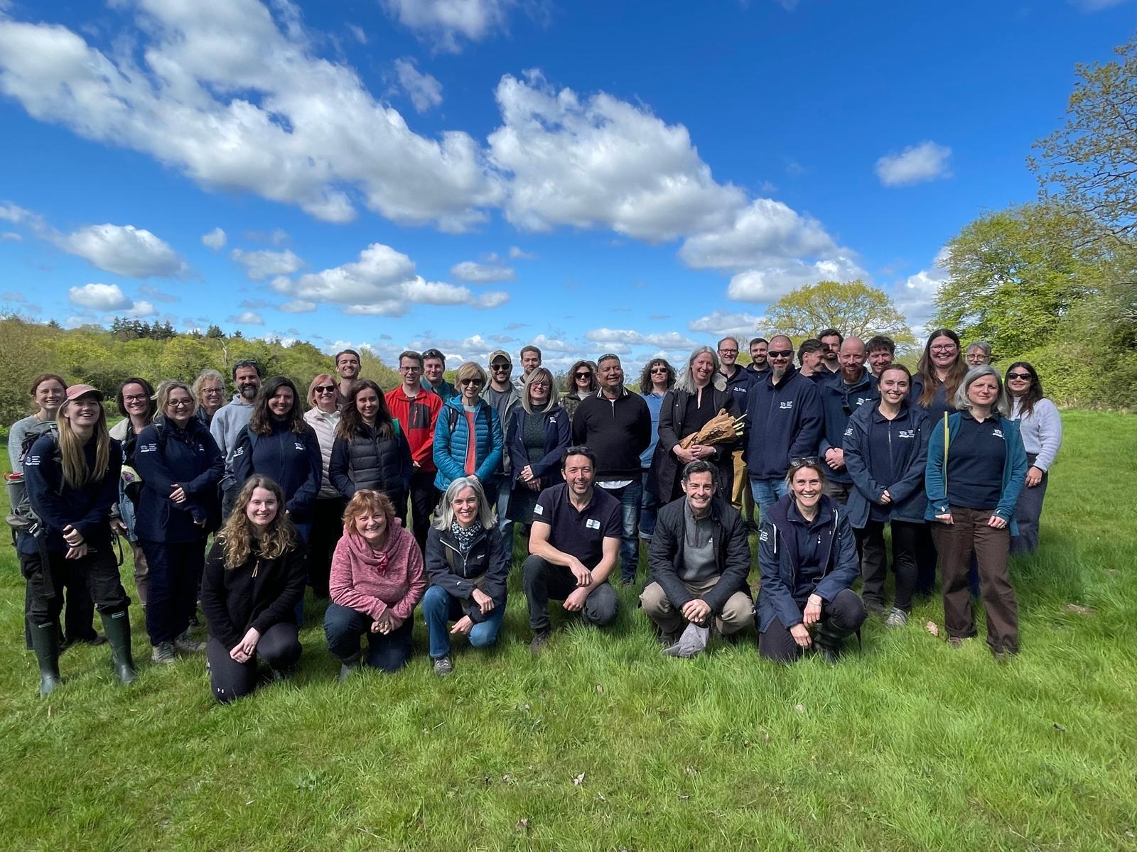 The South East Rivers Trust whole team standing and kneeling for a group photo on a piece of land.