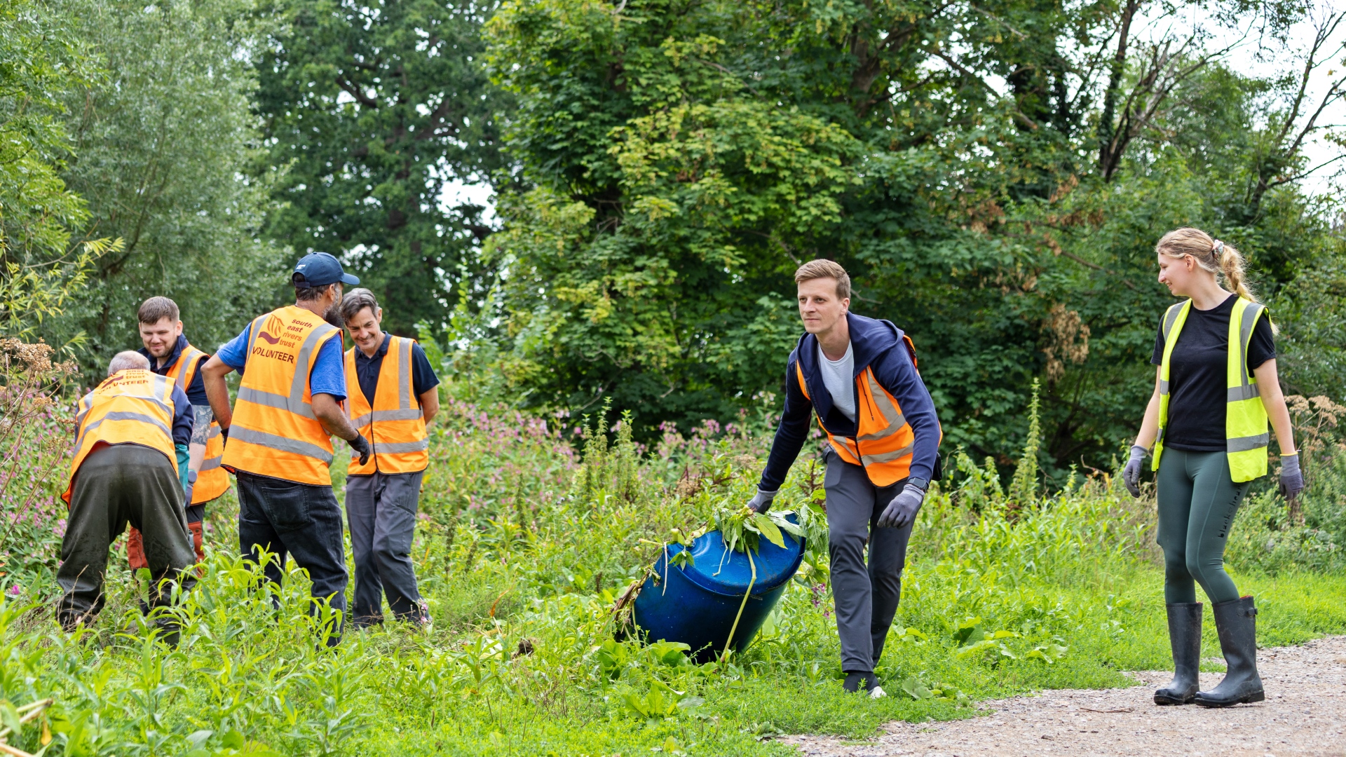 A group of people in high vis vests cleaning up along a river bank.