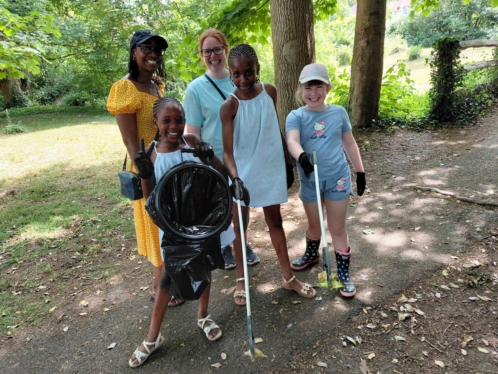 A group of women and children holding litter picking equipment in a park.
