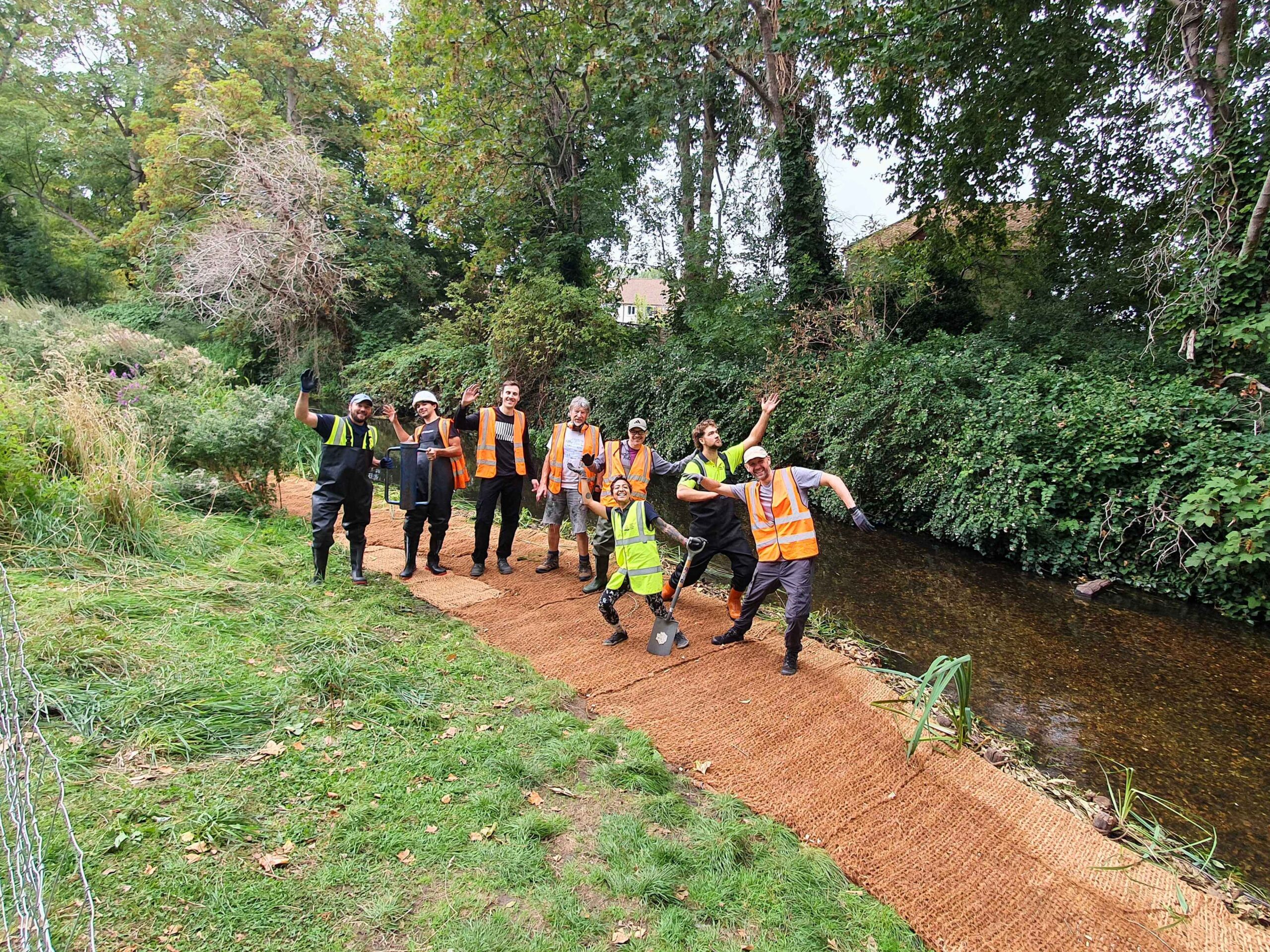 A group of people standing on a newly constructed Berm (shelf) along a river channel.