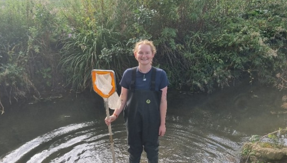 Eilidh stood in a river holding a net